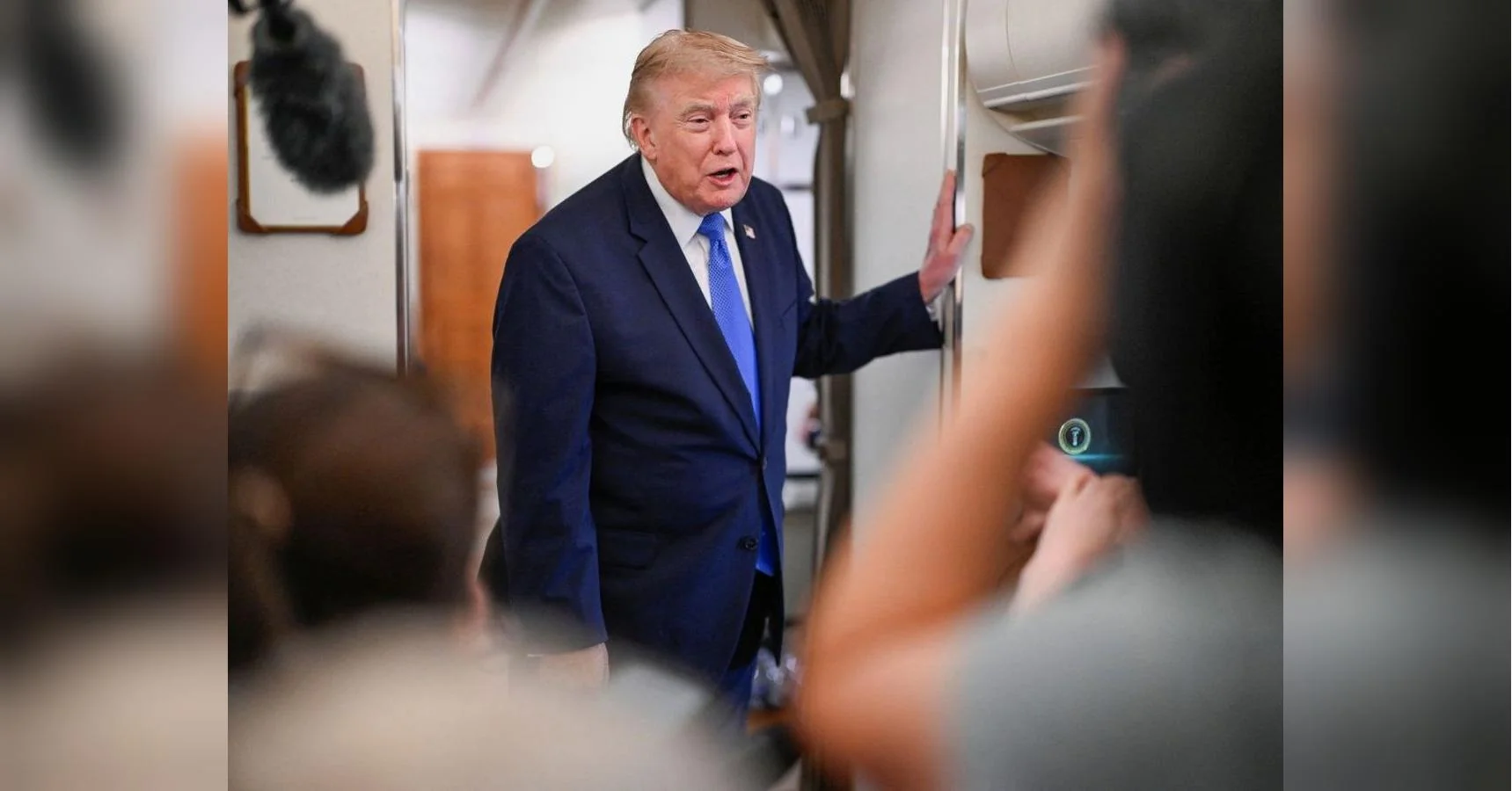Дональд Трамп у синьому костюмі говорить з журналістами в салоні літака